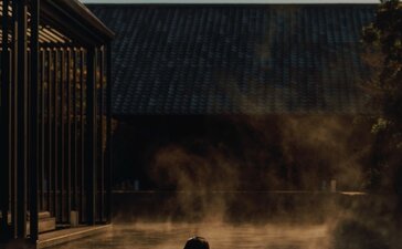 Pessoa a banhar-se num onsen ao amanhecer no resort Amanemu, Japão.