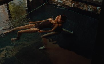 A woman floats peacefully in dark water during a Watsu wellness treatment at Amanemu, Japan.