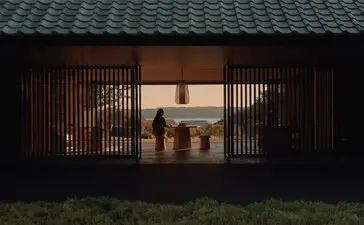 Amanemu resort's welcome pavilion with wooden sliding doors opening to an illuminated interior courtyard at dusk, Japan.
