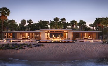 Beachfront villa at Amanvari, Mexico, glowing warmly at dusk along the sand and shoreline.