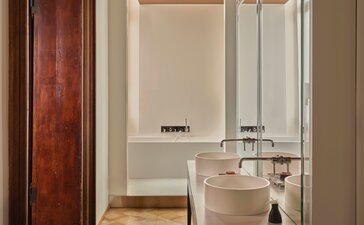 Sansovino Stanza bathroom at Aman Venice, featuring a bathtub, mirror and marble basin.