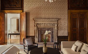 Chambre Sansovino aux tons chauds avec foyer décoratif et mobilier classique, Aman Venice.