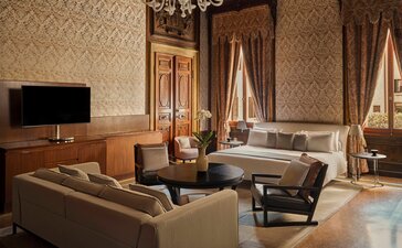 Chambre Sansovino à Aman Venice, avec salon élégant aux tons chauds et mobilier raffiné.