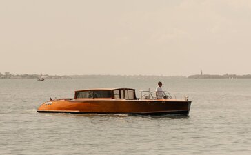 Aman boat gliding through the Venetian Lagoon, Venice, Italy.
