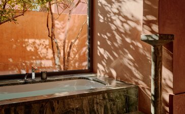 Deluxe Pavilion interior at Amanjena with terracotta walls and plunge pool overlooking the Moroccan landscape.