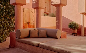 Amanjena リゾートのパビリオン30、テラコッタ色の壁に囲まれた屋外の座席エリア。