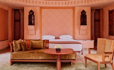 Pavilion bedroom at Amanjena with terracotta walls, traditional Moroccan décor, and seating area.
