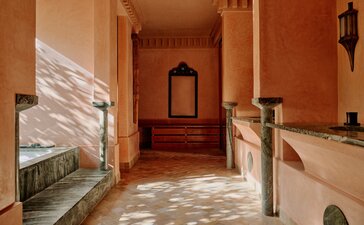 Pool pavilion at Amanjena, Morocco, with terracotta walls and traditional architectural details.