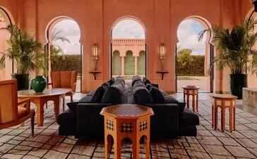 Amanjena villa lounge with terracotta walls, arched doorways and traditional Moroccan furnishings.