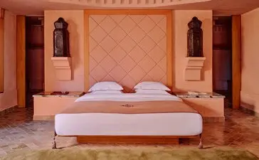 Principal bedroom at Amanjena with symmetrical alcoves and terracotta walls, Morocco.