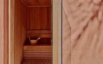 Wooden sauna interior at Amanjena, Morocco, with cedar panelling and bench seating visible through open door.
