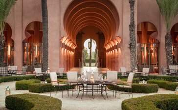 Symmetrical lobby at Amanjena with arched ceilings, central water channel, and paired seating areas flanking manicured gardens.