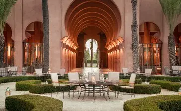 Symmetrical lobby at Amanjena with arched ceilings, central water channel, and paired seating areas flanking manicured gardens.