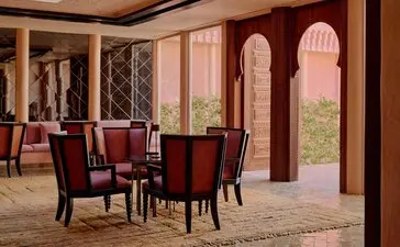 Amanjena dining room with arched doorway opening to Moroccan landscape, warm terracotta tones and traditional furnishings.