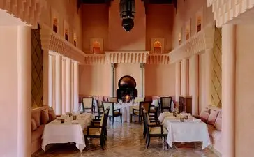 Dining pavilion at Amanjena with terracotta walls and symmetrical table settings in Morocco.