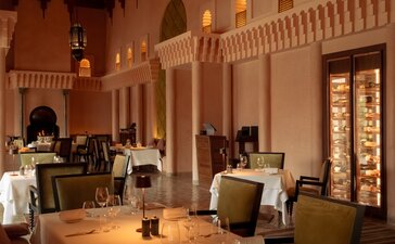 Amanjena's dining venue with arched doorways, warm lighting, and intimate table settings.