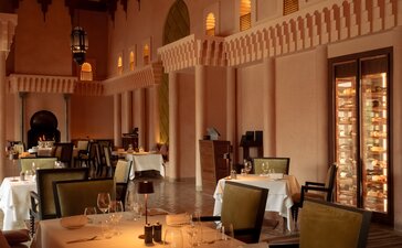 Amanjena's dining venue with arched Moroccan architecture, candlelit tables, and warm ochre walls.