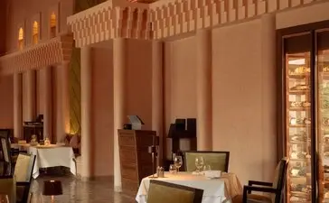 Amanjena resort's food and beverage venue with terracotta walls, ornate columns and warm evening lighting.