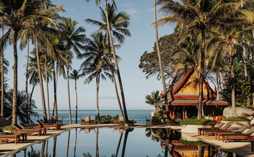 Main pool at Amanpuri resort in Thailand, with palm trees and ocean views.