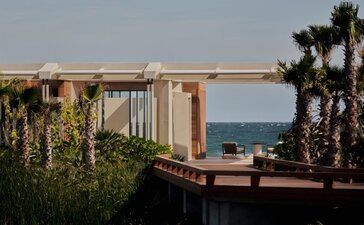 Beachfront casita at Amanvari with ocean views beyond palm trees and coastal vegetation.