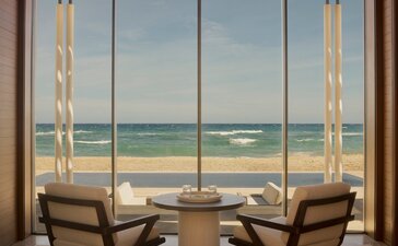 Beachfront casita at Amanvari with two wooden chairs facing expansive ocean views through floor-to-ceiling windows.