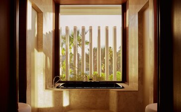 Beachfront casita bathroom at Amanvari with window overlooking wooden coastal architecture.