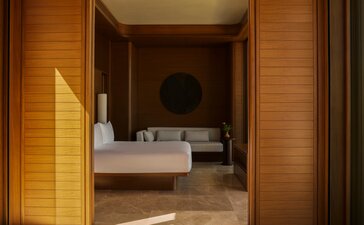Beachfront casita principal bedroom at Amanvari, Mexico, with warm wooden doors and neutral tones.