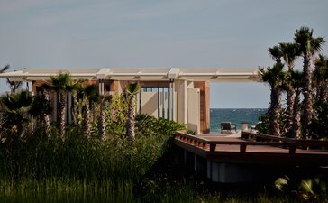Beachfront casita exterior at Amanvari, Mexico, with wooden deck overlooking palm trees and sea.