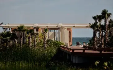 Beachfront casita exterior at Amanvari, Mexico, with wooden deck overlooking palm trees and sea.
