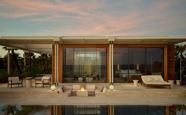 Beachfront casita exterior at Amanvari with illuminated interior viewed across terrace at dusk.