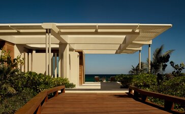 Beachfront casita exterior at Amanvari with shaded pergola and ocean views across terracotta terrace.