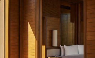 Wooden-framed entrance to an Estuary Casita at Amanvari, Mexico, with warm sunlight streaming across the threshold and a glimpse of the principal bedroom beyond.