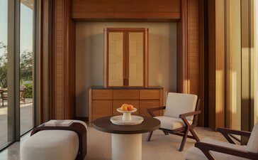 Amanvari Estuary Casita living area with wooden panelled walls, contemporary furniture, and natural light from floor-to-ceiling windows.