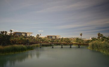 Horizon Casita at Amanvari overlooks a tranquil river with distant buildings and palm trees under a soft sky.