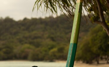 Person holding stand-up paddleboard in shallow turquoise water at Amanwana, Indonesia.