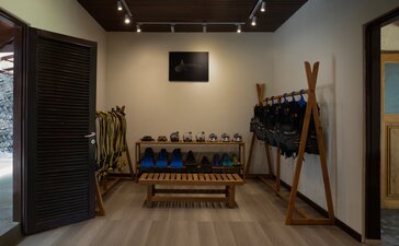Dive centre interior at Amanwana with wooden benches, diving equipment and tools displayed on walls.