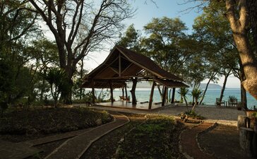 Yoga Shala at Amanwana with wooden structure nestled among trees overlooking the sea at sunset, Indonesia.