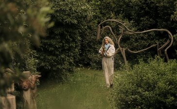 Studio portrait of Alexandra Athanasiades at Amanzoe, Greece, holding a rope among lush greenery.