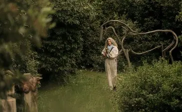 Studio portrait of Alexandra Athanasiades at Amanzoe, Greece, holding a rope among lush greenery.