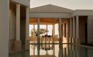 Amanzoe resort interior with wooden folding doors opening onto terrace views of Greece.