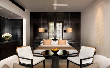 Amansara suite interior with black accent wall, contemporary seating, and ambient lighting.