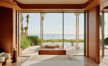 Amanvari accommodation with floor-to-ceiling windows overlooking Mexican landscape and terracotta seating.
