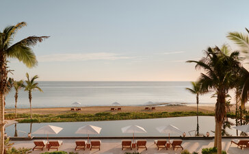 Amanvari's seafront terrace with loungers overlooking calm coastal waters at dusk.