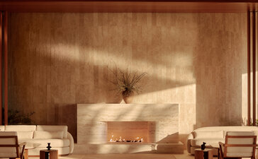 Amanvari's minimalist lounge with travertine fireplace and warm earth-toned walls.