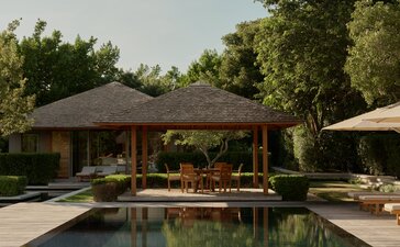 Outdoor dining pavilion at Amanyara overlooking the pool, surrounded by tropical greenery and sun loungers.