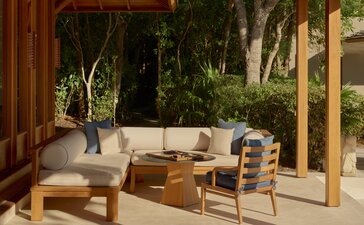 Amanyara villa outdoor living area with wooden seating and tropical views through open doors.