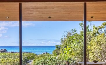 Ocean pool pavilion bedroom with framed views of turquoise Caribbean waters and tropical vegetation at Amanyara.