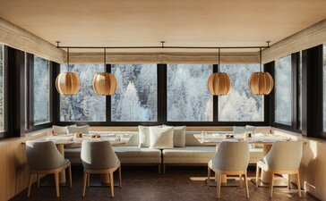 The Heritage Room at Aman Rosa Alpina resort, featuring modern artwork and elegant seating beneath tall windows.