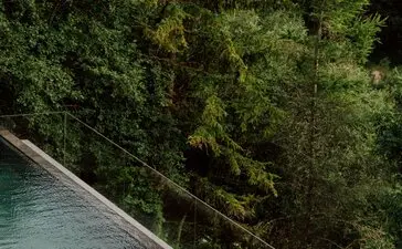 Outdoor pool at Aman Rosa Alpina resort surrounded by Alpine forest.