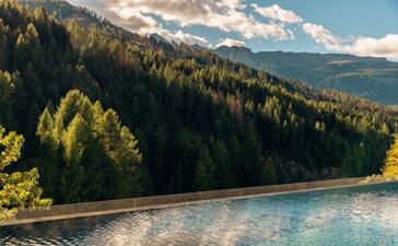 Outdoor pool at Aman Rosa Alpina overlooking alpine mountains and forested valleys, Italy.